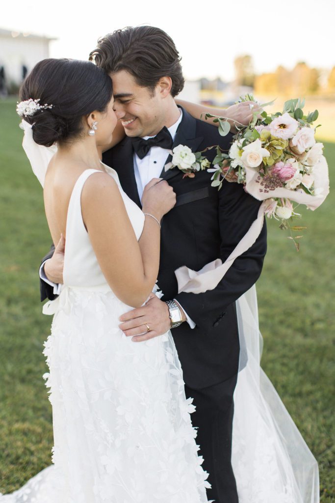 Bride and groom cuddling during sunset with pink floral boquet