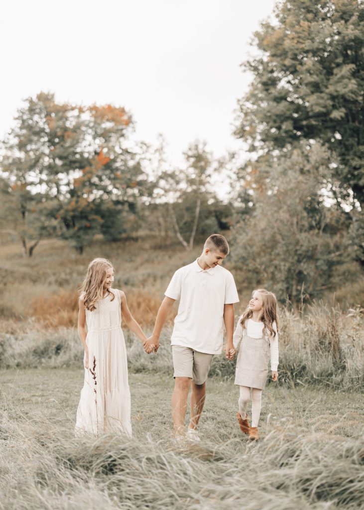Siblings-take-a-walk-in-a-field-for-fall-family-photos.
